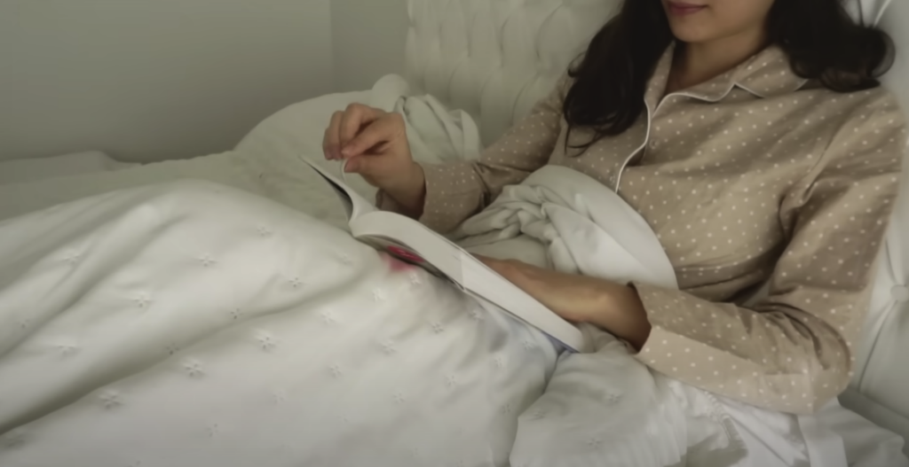 Photo of a girl lying on a bed, happily reading a book